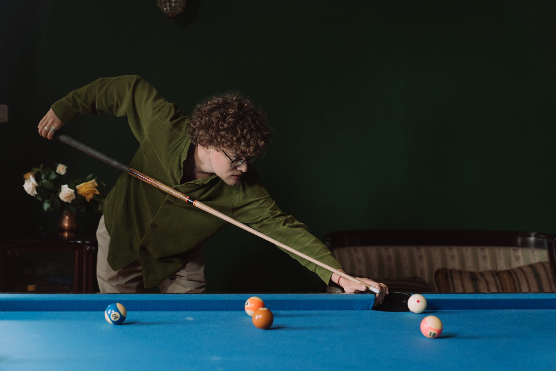 man in green long sleeve shirt playing billiard